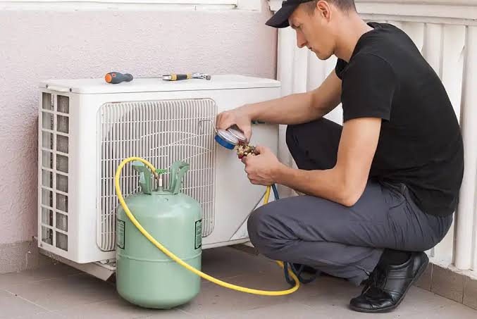 Technician checking refrigerant pressure on an outdoor mini-split air conditioner